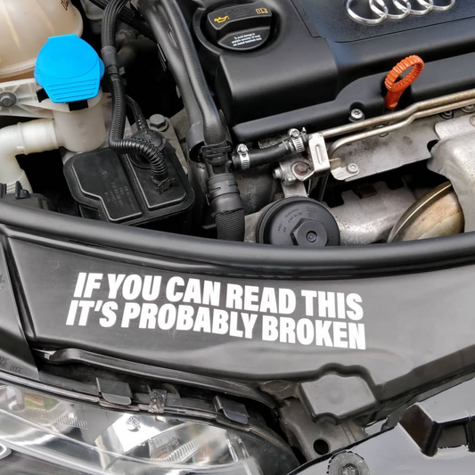 Vinyl decal that reads “If you can read this it’s probably broken” that is applied to surface in engine bay of a car